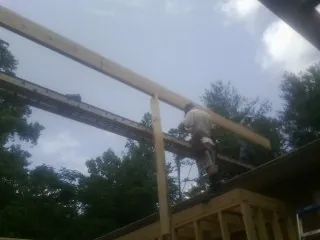 Carpenter setting a ridge beam over a new addition frame — Ice Dam Removal by Roofing Brothers in New Brunswick