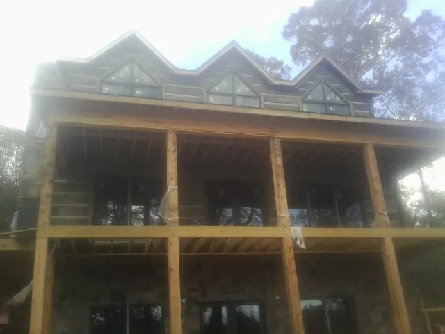 Dormers and porch framing on a large log home under construction — Roof Coating work by our crew in New Brunswick