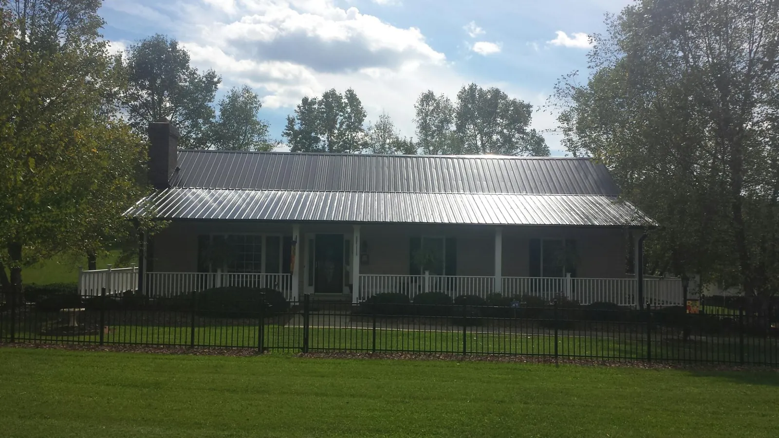 Gray metal roof on a brick ranch with a full width front porch — Gutter Guard Installation work by our crew in New Brunswick