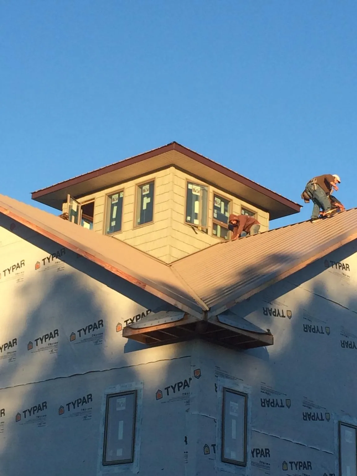 Roofers working around a rooftop cupola on a new metal roof at sunset — Roof Waterproofing in New Brunswick by Roofing Brothers
